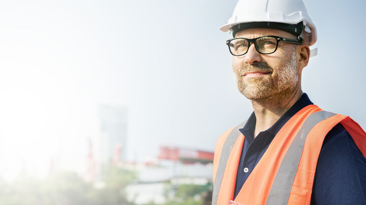 Mann mit oranger Warnweste und weißem Helm