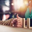 Businesswoman stops a chain fall like domino game toy. Concept of preventing crisis and failure in business