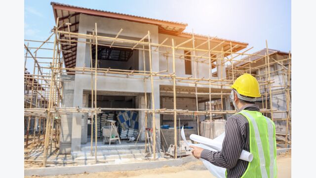 Professional engineer architect worker with protective helmet and blueprints paper at house building construction site background