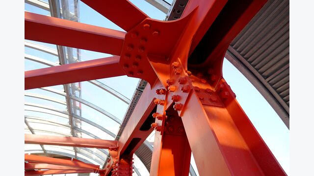 Red iron beams bolted on. Angular connection of several iron beams in one place. Pedestrian crossing with iron construction and glass ceiling.