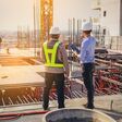 Structural engineer and foreman worker with touch pad discuss, plan working for the outdoors building construction site.