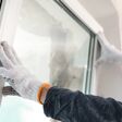 Worker installing plastic window indoors, closeup view