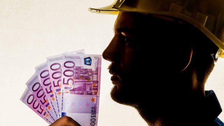 Ein Arbeiter in einem Gewerbebetrieb ( Handwerker ) mit Geldscheinen in der Hand