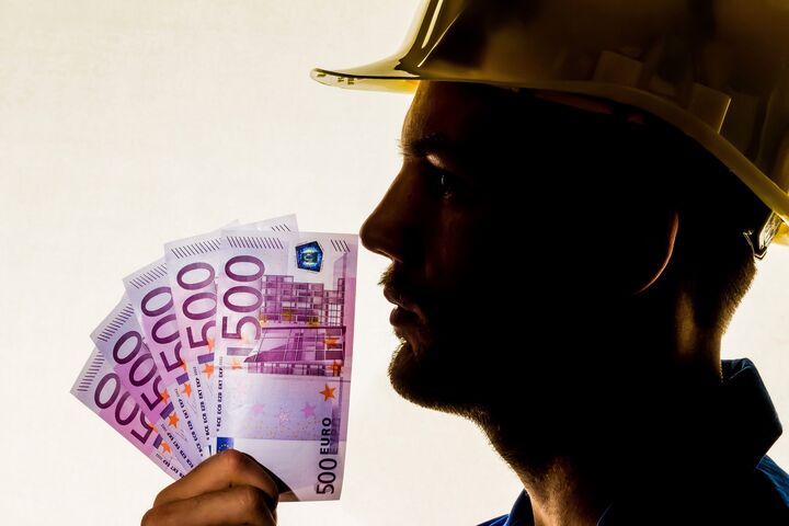 Ein Arbeiter in einem Gewerbebetrieb ( Handwerker ) mit Geldscheinen in der Hand