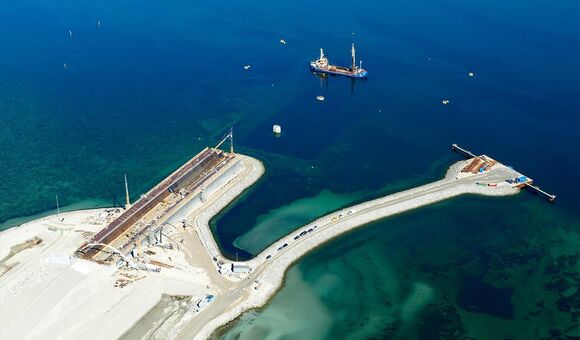 Blick auf die Baustelle der neuen Storstrøm-Brücke: Auf der künstlichen Arbeitsfläche am Meer entstehen die großen Brückenelemente, während Doka die Schalungs- und Traggerüstlösungen für die Produktion liefert.