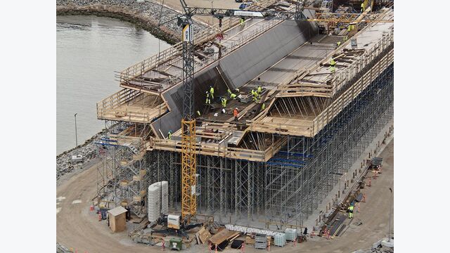 Aufwendige Geometrie in der Ausführung: Arbeiter montieren und betonieren an den schrägen Bauteilflächen, die hohe Anforderungen an Schalung, Zugang und Baustellenlogistik stellen.