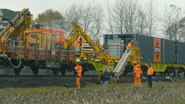 Der komplette Maschinenzug bündelt Materialtransport, Zuführung und Verlegung auf dem Gleis. Personal begleitet den Prozess, kontrolliert die Einbaulage und greift an Sonderstellen ein.