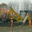 Der komplette Maschinenzug bündelt Materialtransport, Zuführung und Verlegung auf dem Gleis. Personal begleitet den Prozess, kontrolliert die Einbaulage und greift an Sonderstellen ein.