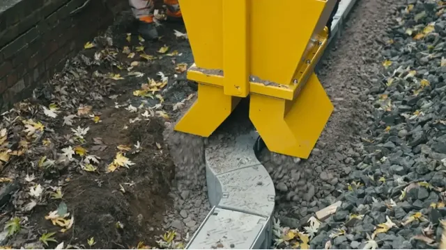 Die Verlegeeinheit bringt das Bettungsmaterial direkt neben dem Gleis ein und führt den Kabeltrog in einem kontinuierlichen Arbeitsgang durch Kurven und entlang wechselnder Trassenverläufe.