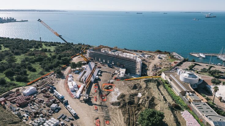 Direkt an der Küste von Taranto entsteht das neue Schwimmstadion für die Mittelmeerspiele 2026. Das Hallendach wird von 26 gebogenen Brettschichtholzbindern getragen, die bis zu 51,8 Meter lang sind.