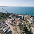 Direkt an der Küste von Taranto entsteht das neue Schwimmstadion für die Mittelmeerspiele 2026. Das Hallendach wird von 26 gebogenen Brettschichtholzbindern getragen, die bis zu 51,8 Meter lang sind.
