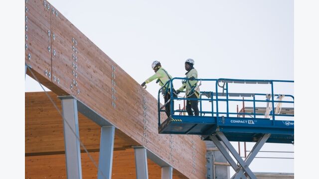 Im fertigen Innenraum bleiben die gebogenen Holzbinder sichtbar. Die zwischen ihnen angeordneten CLT-Platten schließen das rund 3.800 Quadratmeter große Dach über dem Hallenbecken.