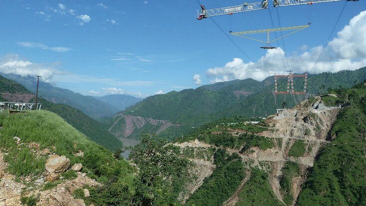 Ein Traversen-Gestell schwebt am Kabelkran über der Chenab-Schlucht: Zwei parallele Systeme mit je 20 Tonnen Tragfähigkeit brachten Stahlteile dorthin, wo kein Bodenkran hinreichte.