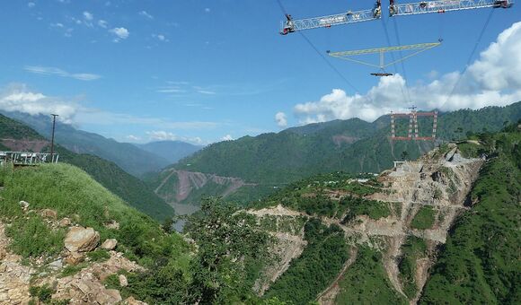 Ein Traversen-Gestell schwebt am Kabelkran über der Chenab-Schlucht: Zwei parallele Systeme mit je 20 Tonnen Tragfähigkeit brachten Stahlteile dorthin, wo kein Bodenkran hinreichte.