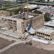 Im Bauzustand wird die Konstruktion hinter der späteren Fassade sichtbar: Gebogene Brettschichtholzträger spannen zwischen den massiven Hallenvolumen und formen den zentralen Zwischenraum der EVE Music Hall.