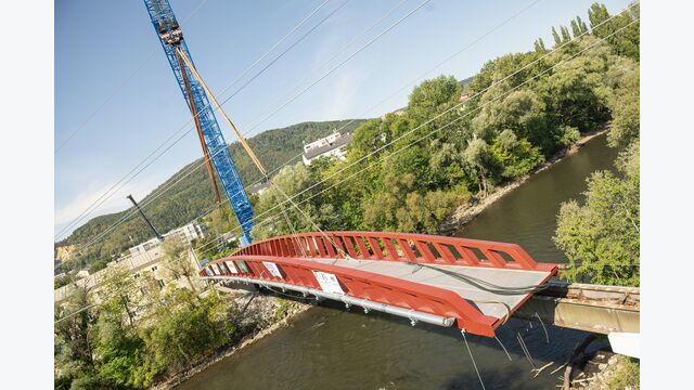 Der neue Steg überspannt die Mur ohne Stütze im Fluss. Während des Einhubs stand der 1968 errichtete und seit 2023 gesperrte Vorgänger noch unmittelbar daneben.