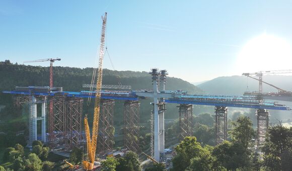 Hoch über dem Neckartal wächst die Hochbrücke Horb zusammen. Für die Montage der schweren Stahlbauteile kam unter anderem ein 700-Tonnen-Raupenkran zum Einsatz; die Fahrbahn liegt später rund 70 Meter über dem Tal.
