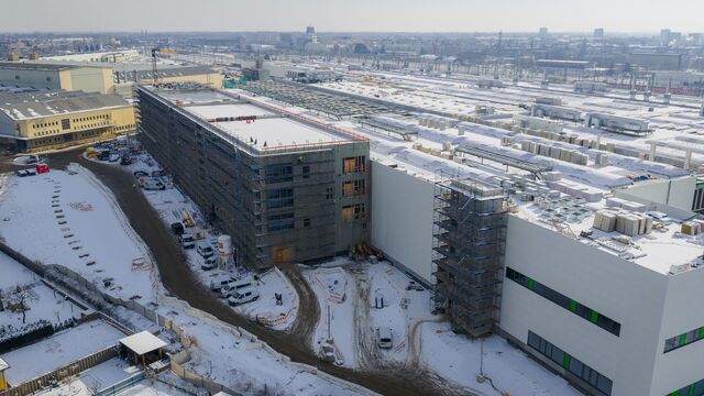 Die Dimension zeigt sich auch aus der Nähe: Am Kopf der neuen Halle laufen Fassaden-, Ausbau- und Außenarbeiten parallel, während auf dem Dach bereits große Teile der technischen Anlagen montiert sind.