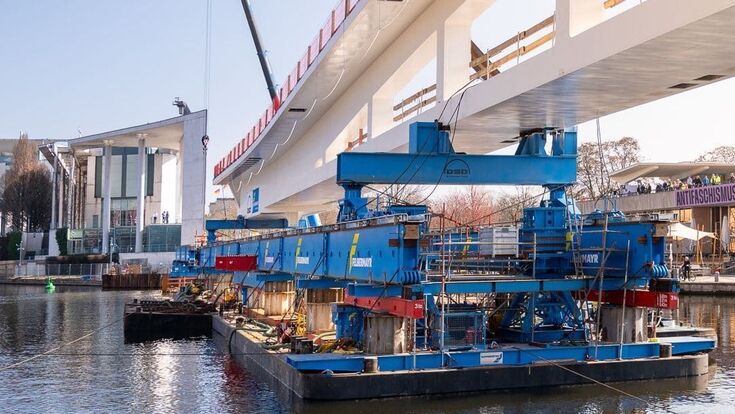 Eine rund 1.500 Tonnen schwere Stahlbrücke wird am Berliner Bundeskanzleramt über die Spree verschoben. Für die aufwendige Montage setzte die österreichische Felbermayr-Gruppe unter anderem schwimmende Pontons und spezielle Schwerlasttechnik ein.