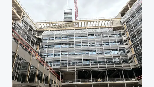 Bauarbeiten im Innenhof des Landesdienstleistungszentrums: Während die Fassade bereits weit fortgeschritten ist, werden weitere Bauelemente per Kran eingehoben. Die ARGE HABAU–SWIETELSKY setzt das Großprojekt in Holz-Hybridbauweise um.