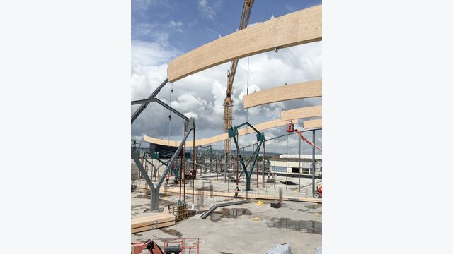 Großformatige Brettschichtholzträger werden auf der Baustelle montiert. Die längsten Primärträger der Dachkonstruktion erreichen im zusammengesetzten Zustand bis zu 45 Meter.