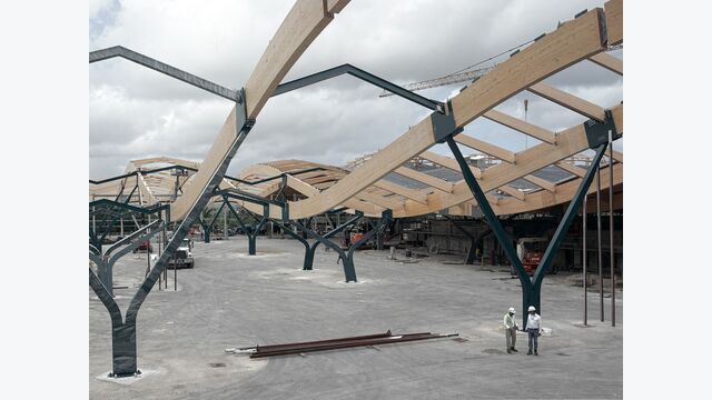 Die geschwungene Dachlandschaft prägt bereits während der Bauarbeiten das Erscheinungsbild des Terminals. Primär- und Sekundärträger aus Brettschichtholz bilden das Tragwerk.